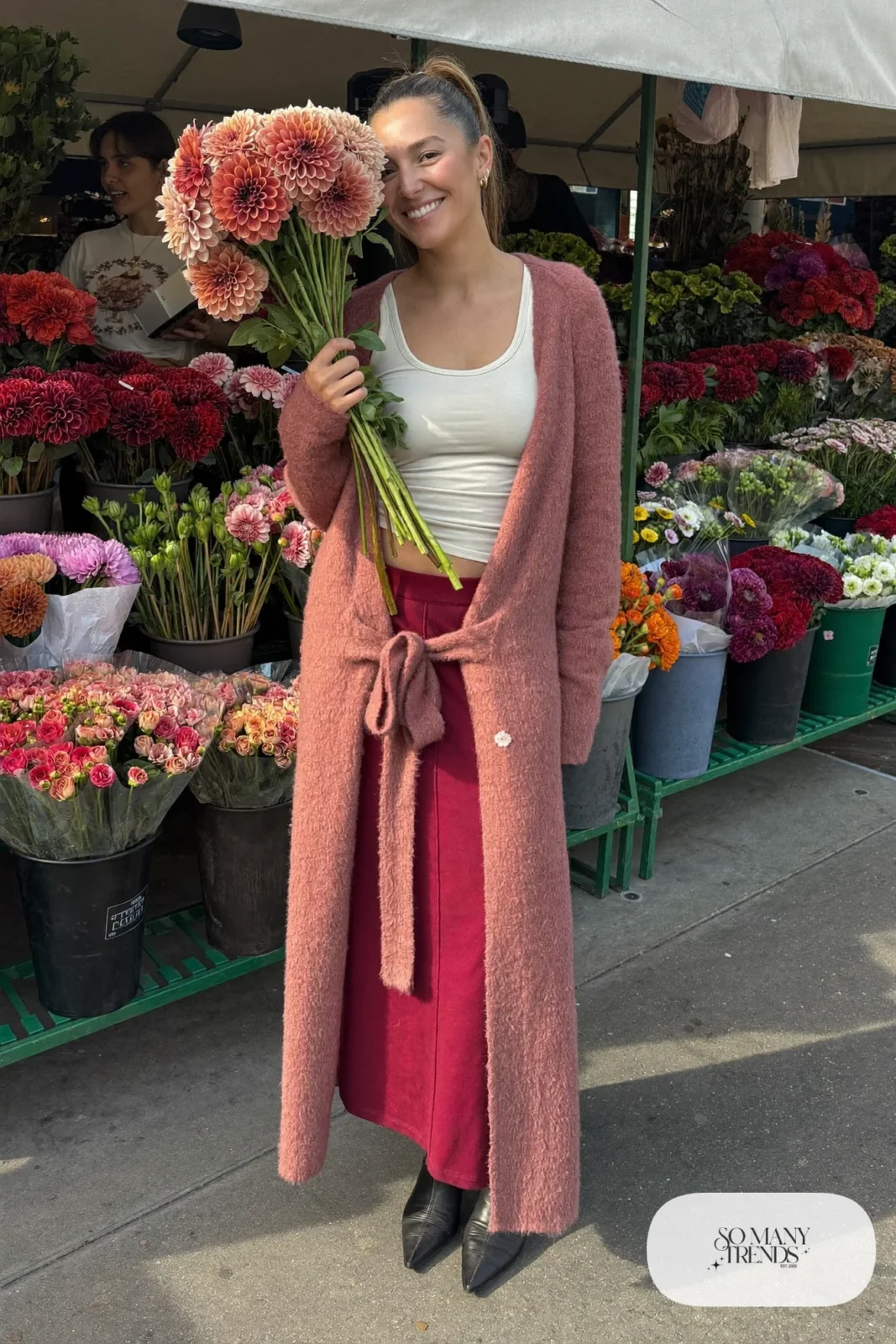 Woman in long pink knit cardigan coat, cream tank, burgundy column maxi skirt and black pointed boots, outfit 11