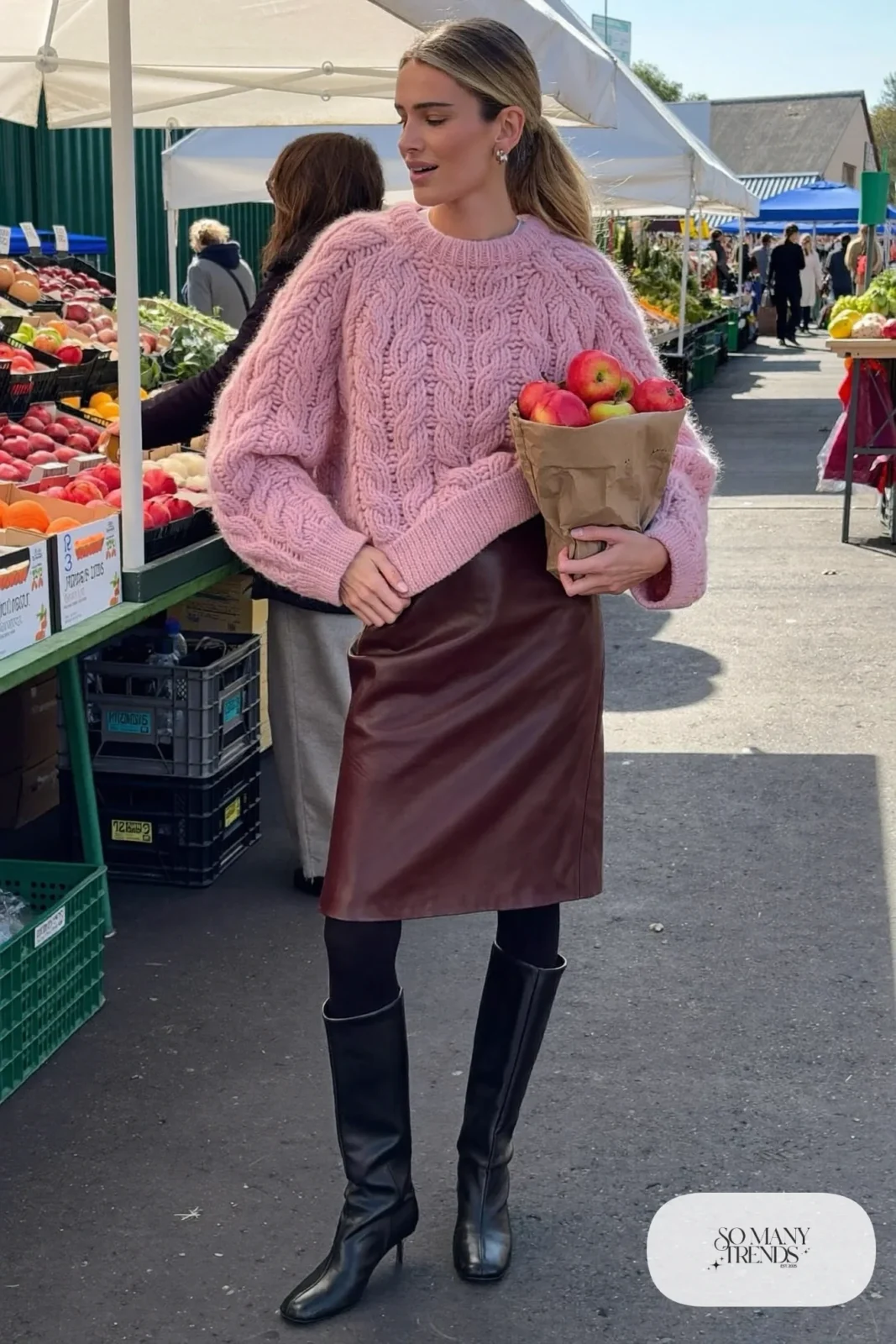 Woman in chunky pink cable-knit sweater, burgundy faux leather midi skirt, black tights and black tall boots, outfit 16