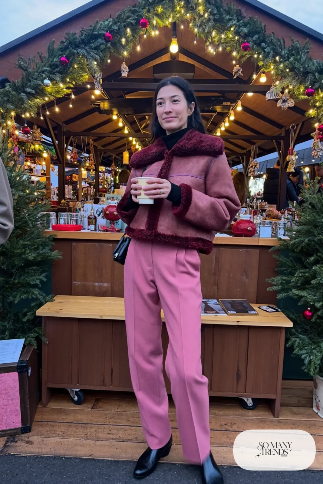 Woman in wine faux shearling jacket, black turtleneck, dusty-pink straight pants and black chelsea boots, outfit 17