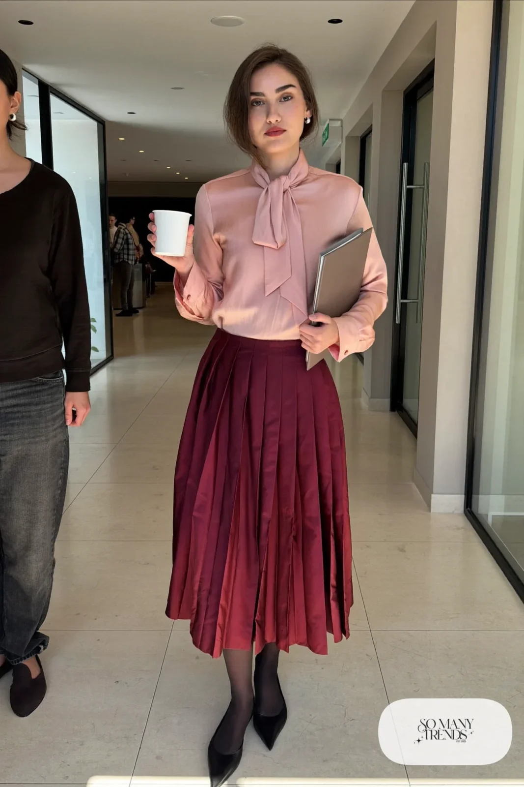 Woman in pink silk bow blouse, burgundy pleated midi skirt, sheer tights and black pointed flats, outfit 18
