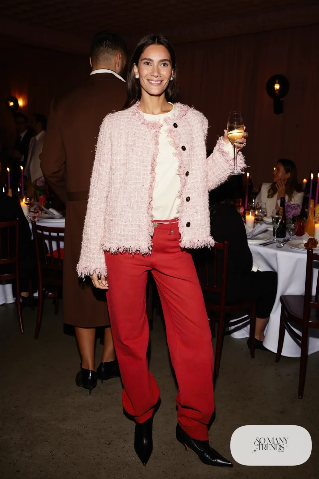 Woman in a cropped pink tweed jacket, cream tee, high-waisted red flared pants and black heeled boots, outfit 7