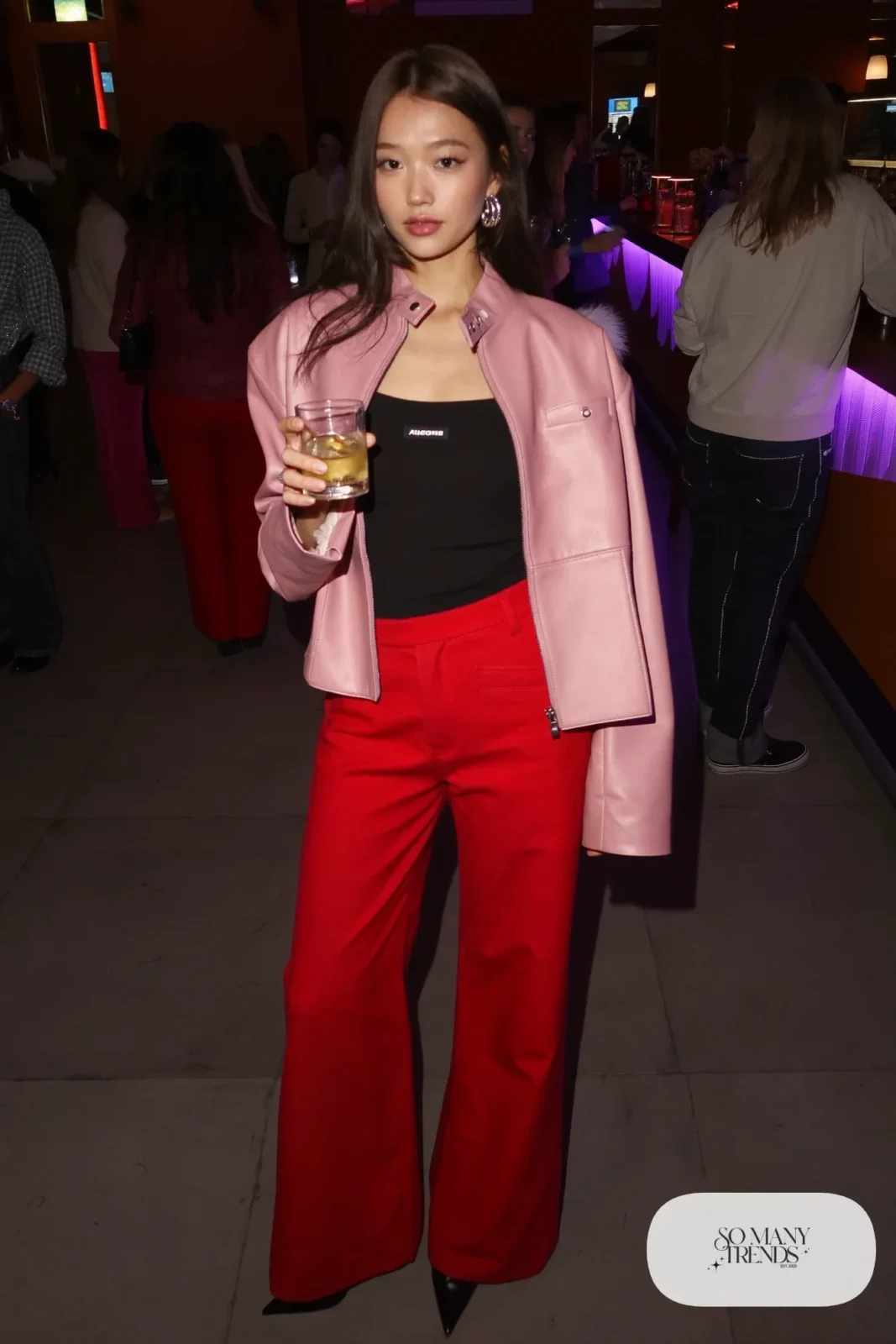 Woman in a cropped pink leather jacket, black tank, red silk wide-leg pants and black strappy-free pointed boots, outfit 10