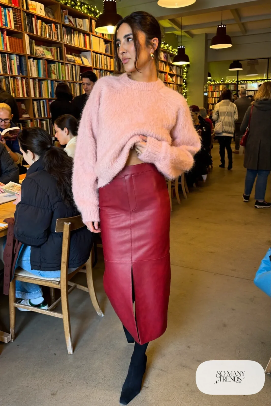 Woman in a blush pink fuzzy crewneck sweater, red faux-leather midi skirt, sheer tights and black ankle boots, outfit 13