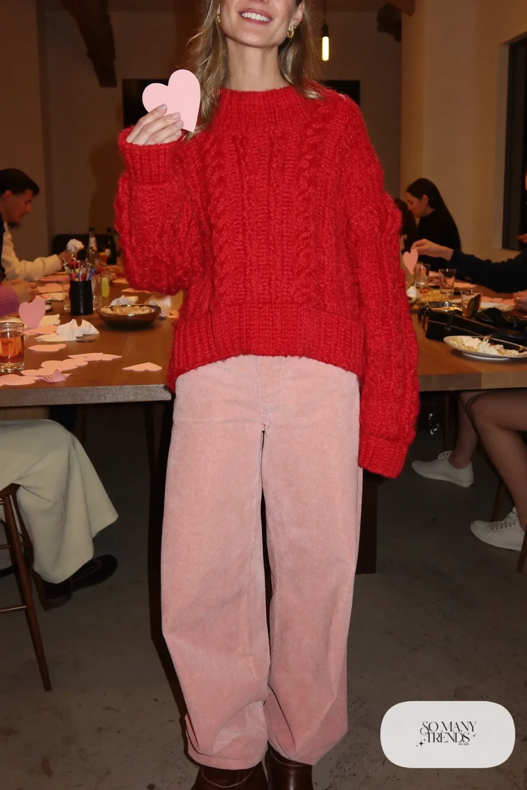 Woman in a chunky red cable-knit sweater, wide pink corduroy pants and brown leather boots, outfit 28