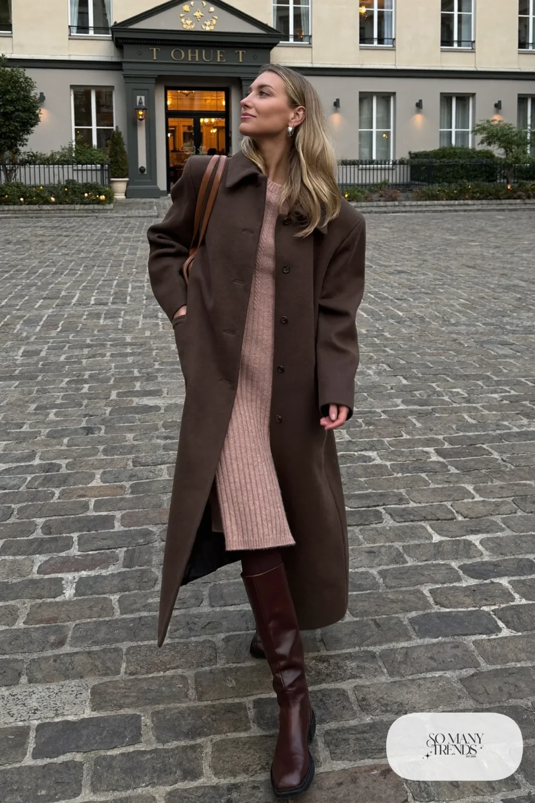 Woman in a chocolate brown cocoon coat over a blush ribbed knit midi dress, brown tights and tall brown boots, outfit 2