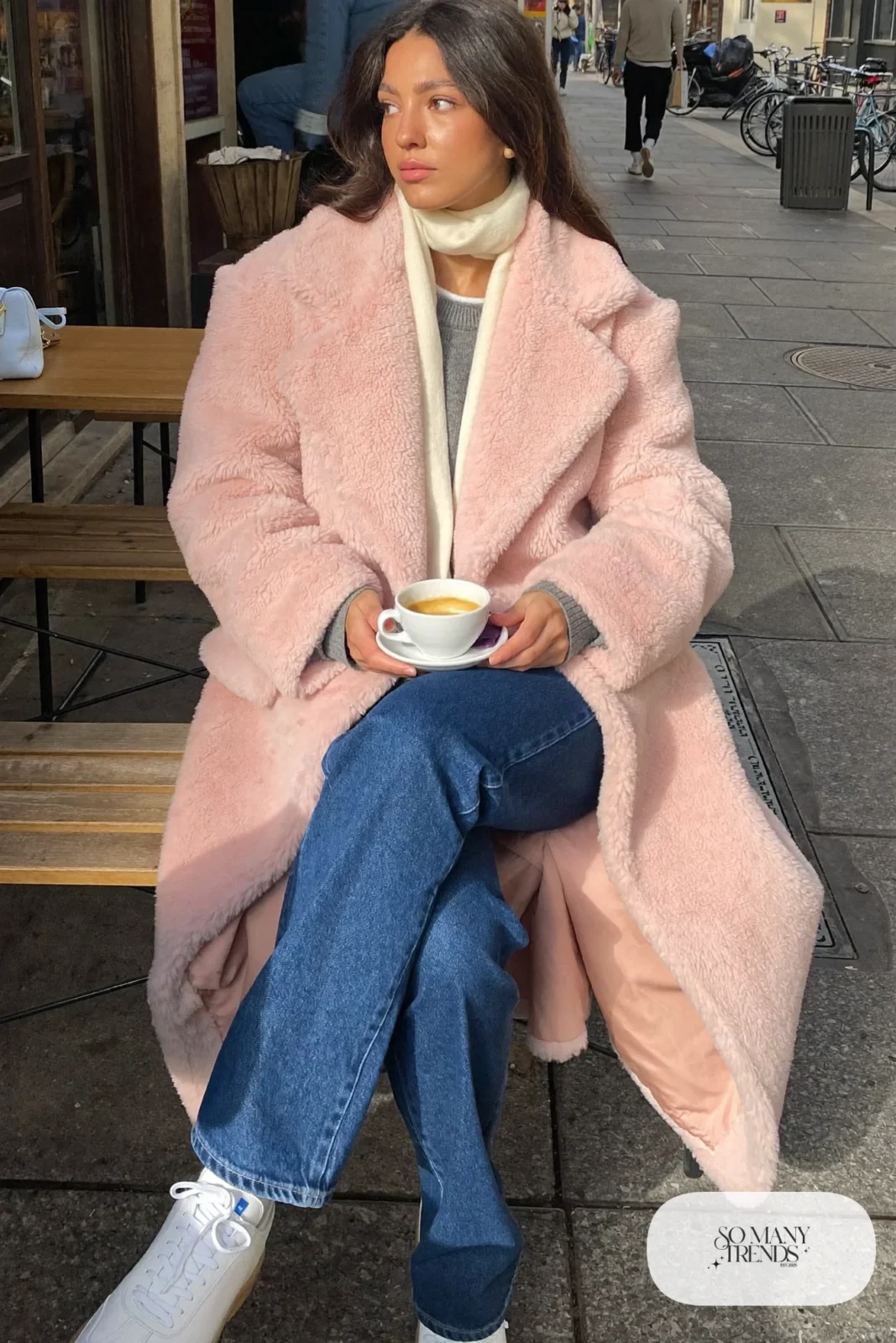 Woman in a blush teddy coat, gray crew sweater, straight indigo jeans and white leather sneakers, outfit 15