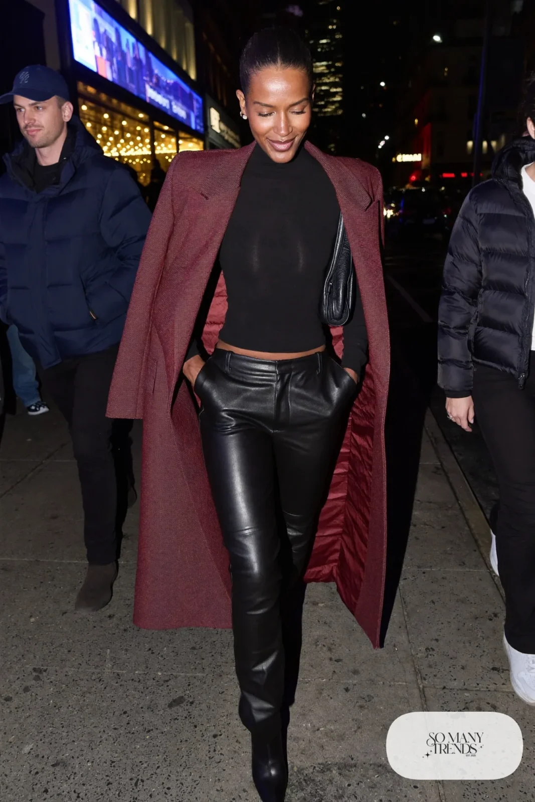 Woman in a long burgundy coat over a black knit top, straight black faux leather pants and black pointed boots, outfit 21