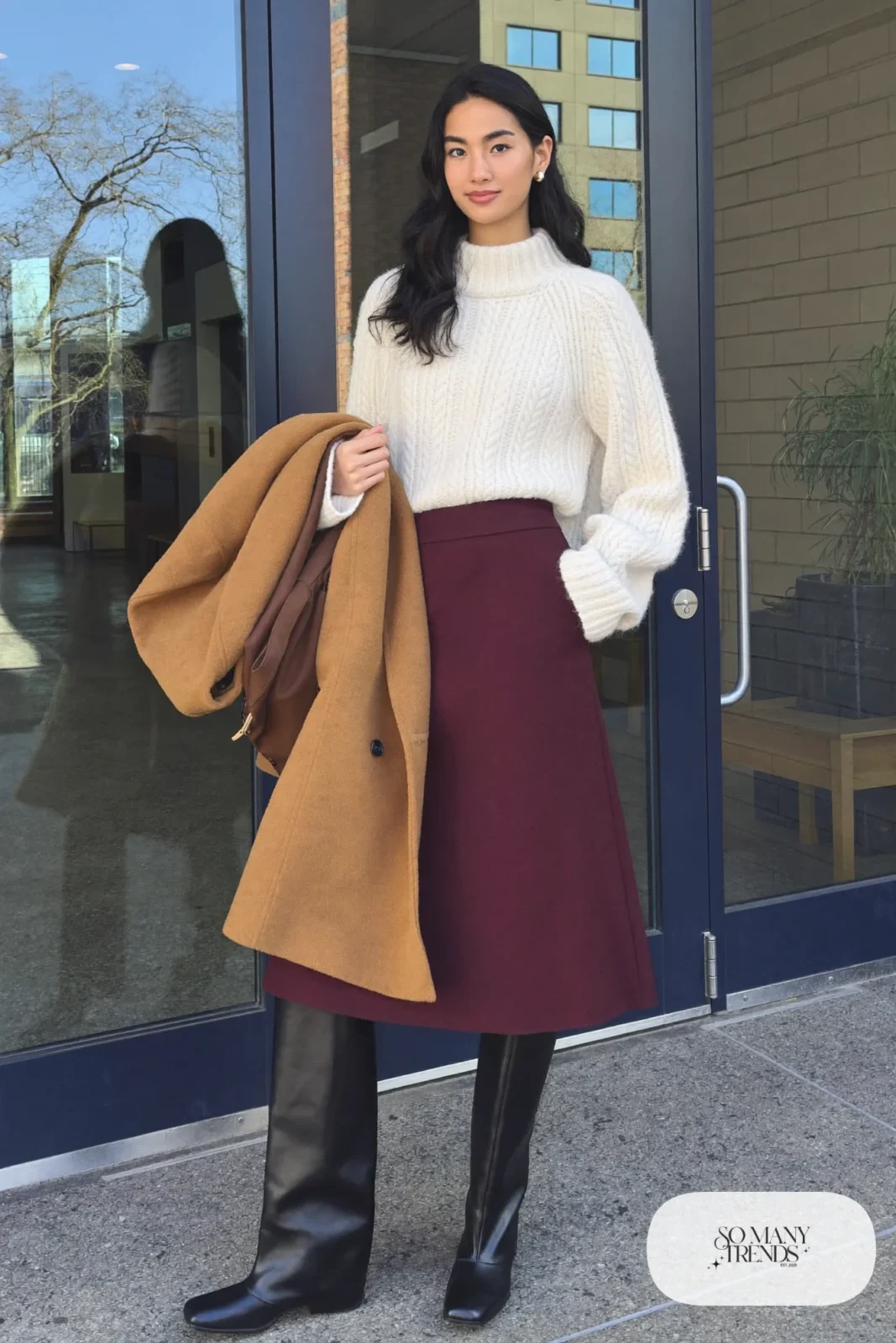 Woman in ivory knit sweater, burgundy wool midi skirt, black knee-high boots and camel coat, outfit 2