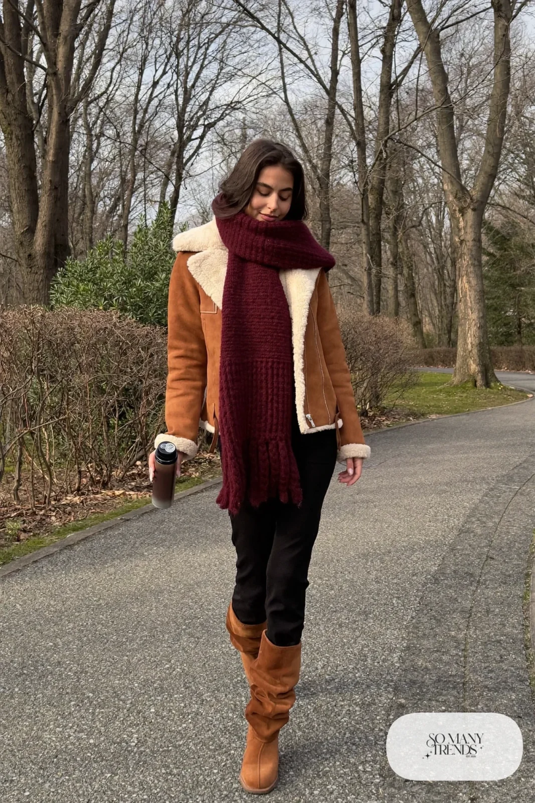 Woman in tan shearling-collar jacket, black slim pants and cognac suede boots with burgundy scarf, outfit 10