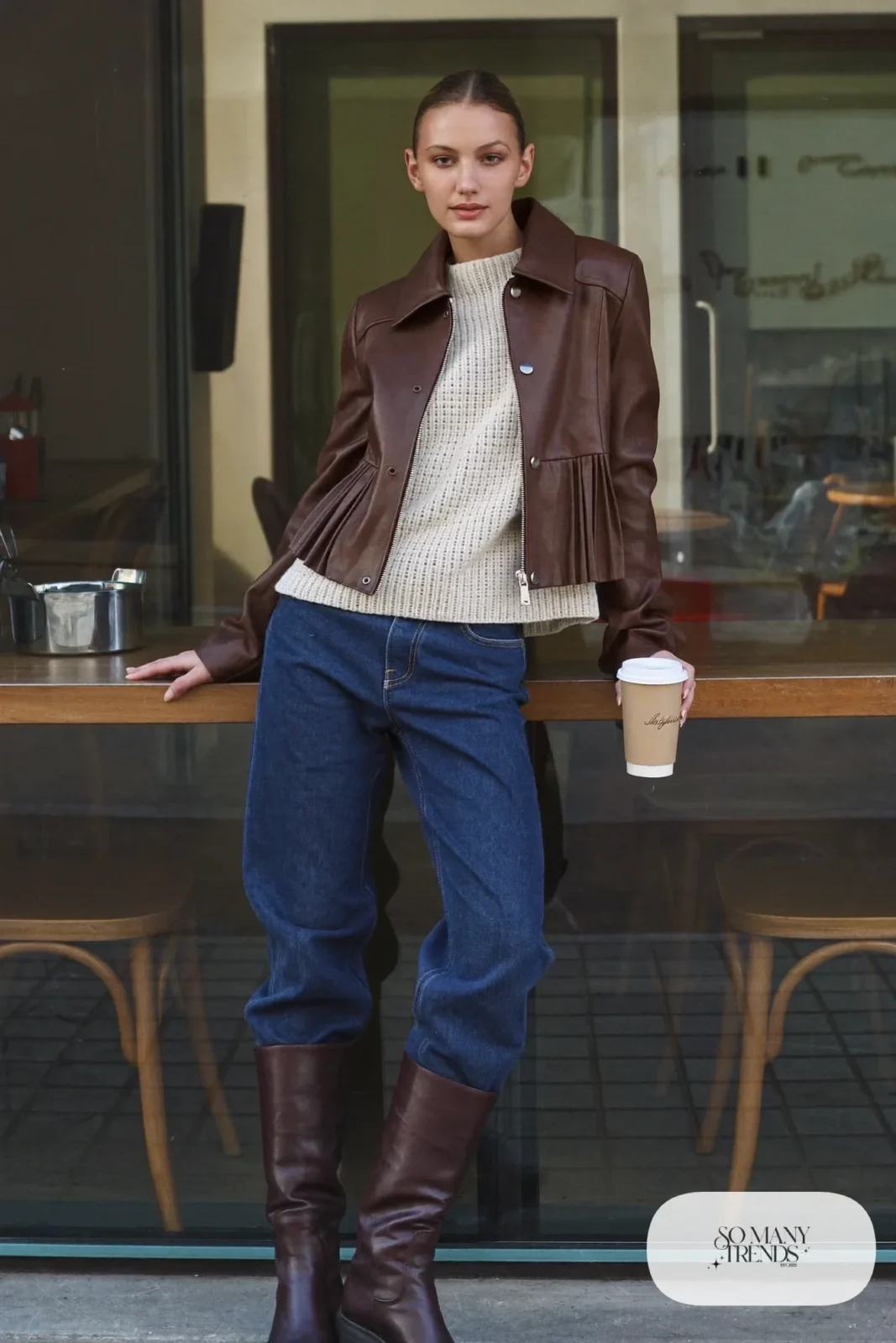 Woman in brown leather jacket, cream knit, dark straight jeans and chocolate leather boots, outfit 16