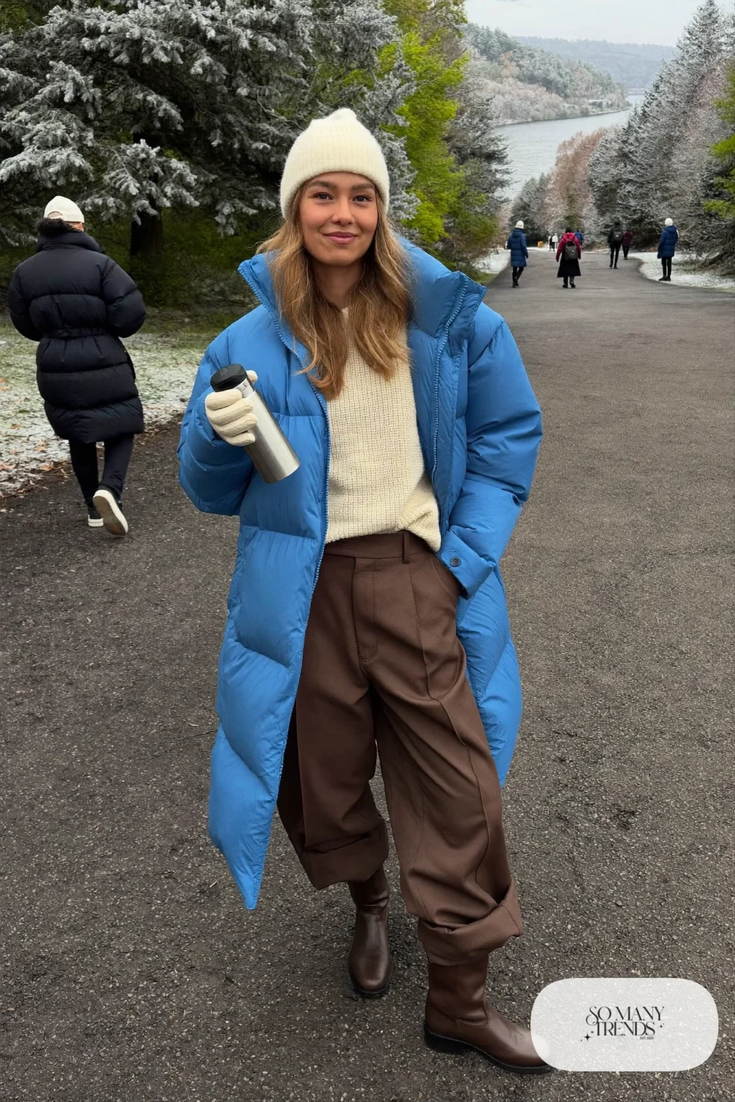 Woman in baby blue matte puffer coat, chocolate brown wide-leg pants, cream sweater and brown boots, outfit 21