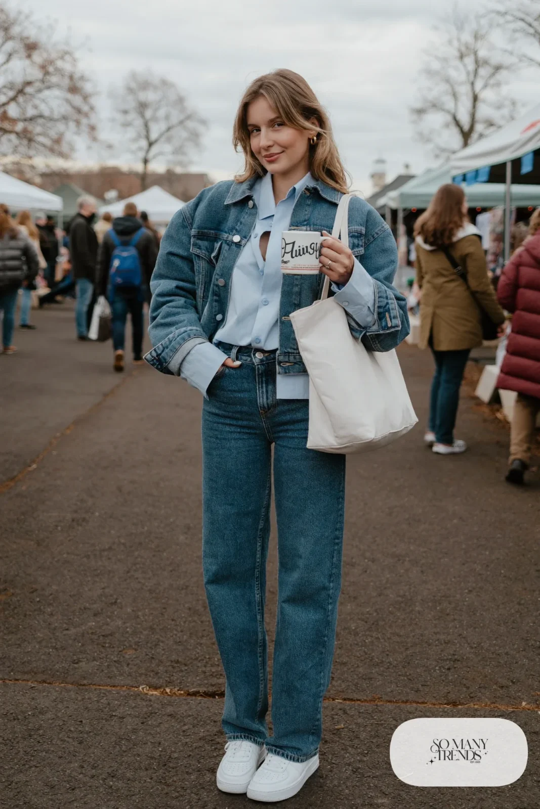 Woman in pale blue shirt, mid-blue straight jeans, dark denim cropped jacket and white sneakers, outfit 23