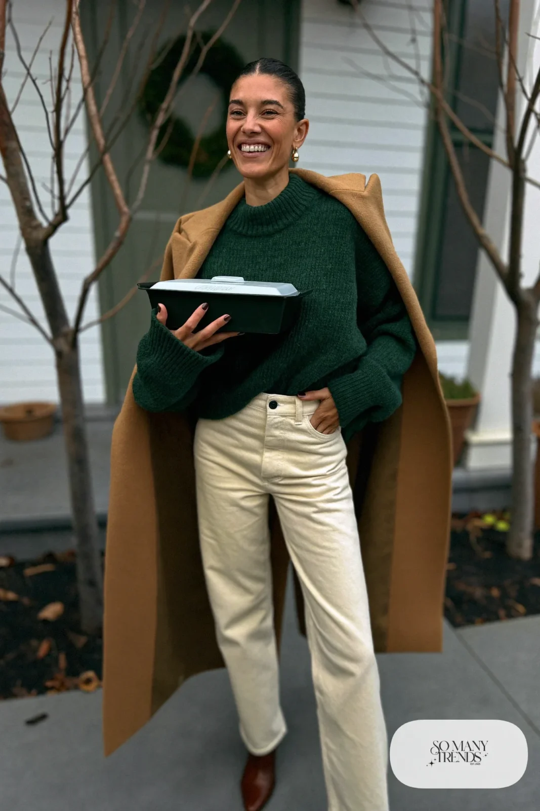 Woman in forest green chunky sweater, cream straight jeans, brown leather boots and a camel coat, outfit 25