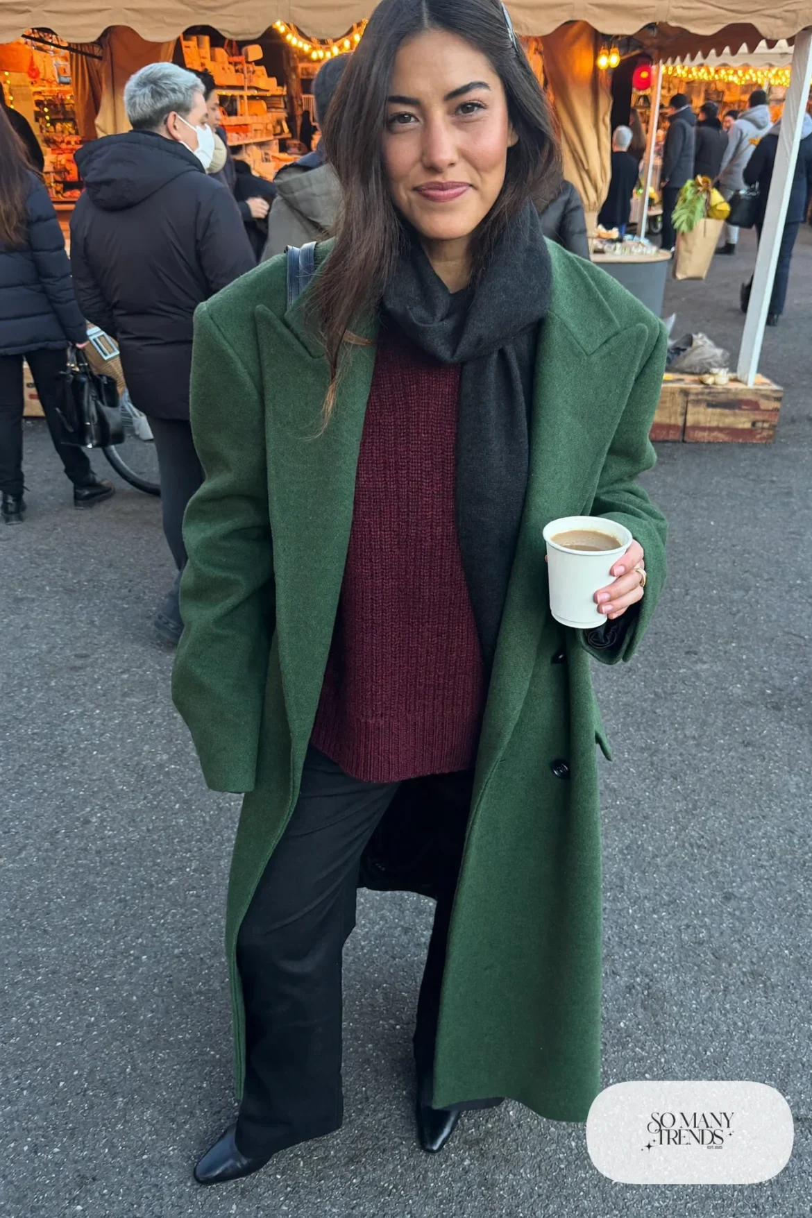 Woman in forest green wool coat, burgundy sweater, black pants and black boots with a black scarf, outfit 27