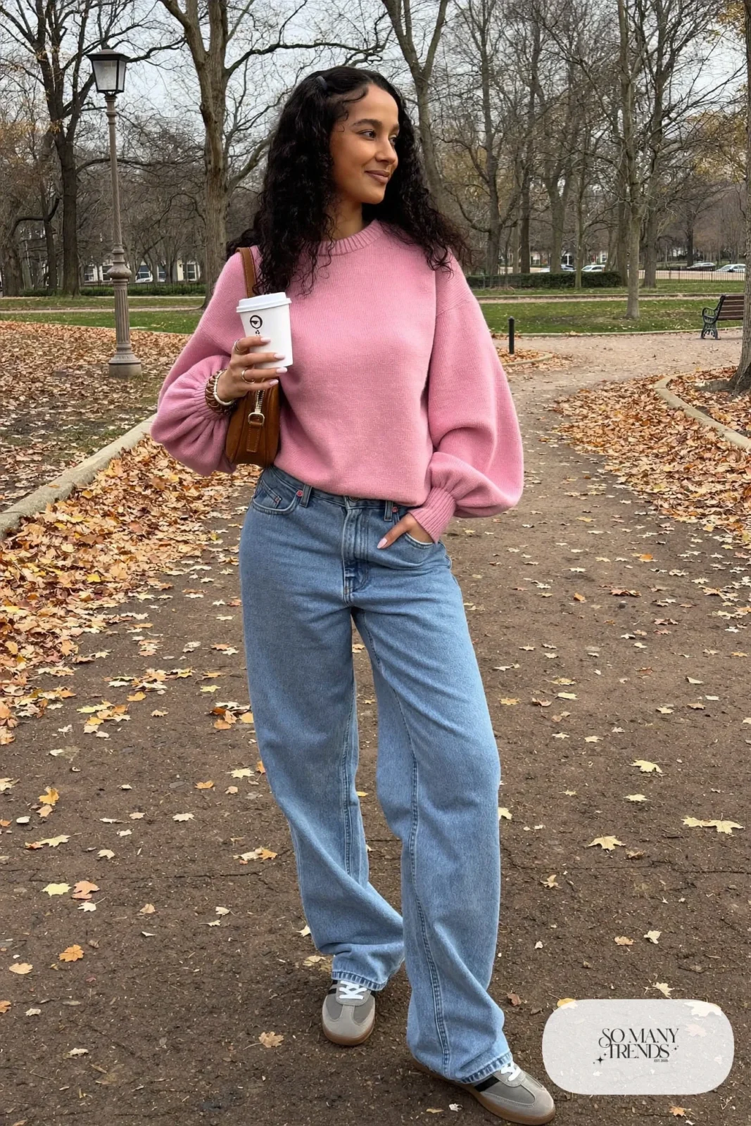 Woman in baggy faded blue jeans, dusty pink puff-sleeve knit, gray sneakers and a crossbody bag, look 8