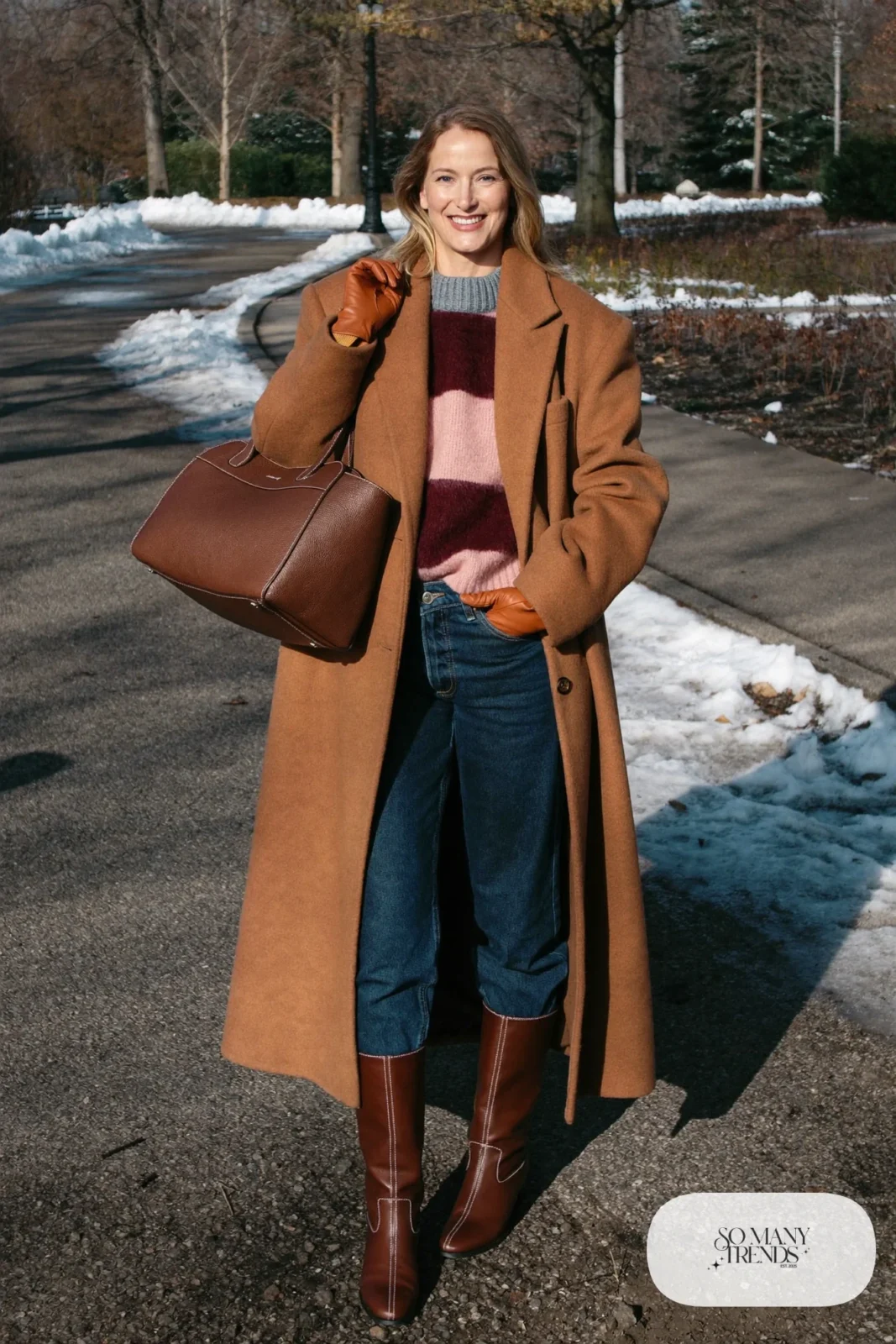 Woman in straight jeans tucked into brown boots, gray and burgundy patterned sweater and wool coat, look 20