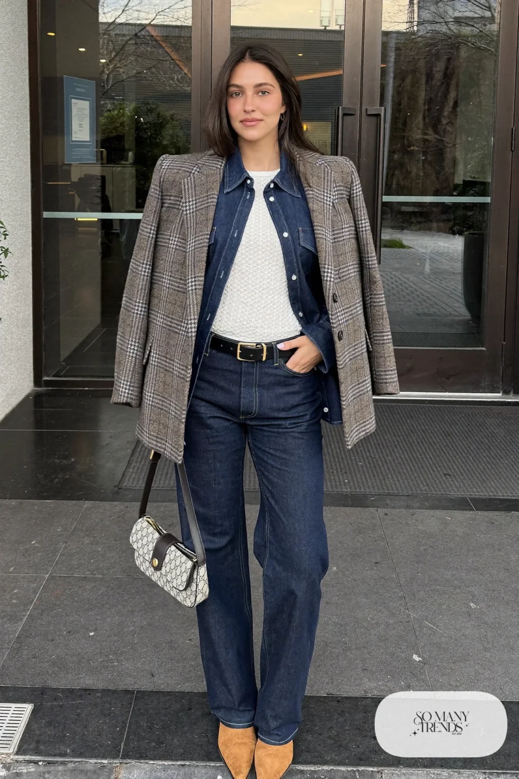 Woman in dark straight jeans, indigo denim shirt, check double-breasted blazer and tan western boots, look 22