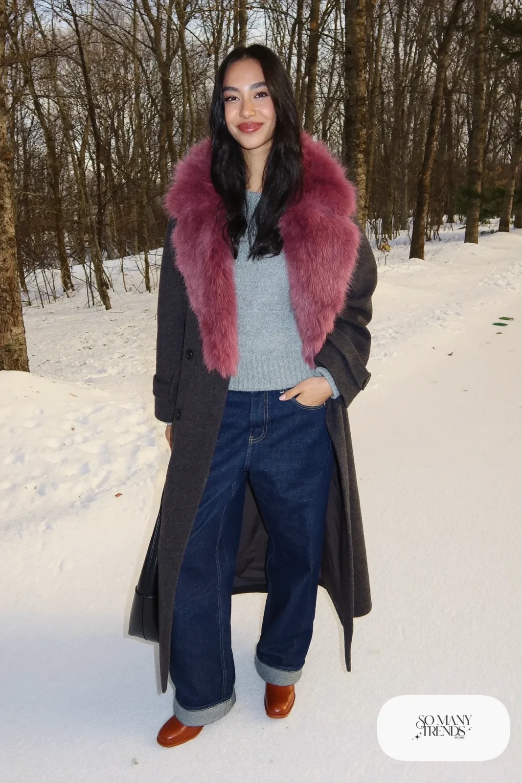 Woman in barrel jeans, long coat with burgundy faux fur collar, gray knit and cognac boots, look 28