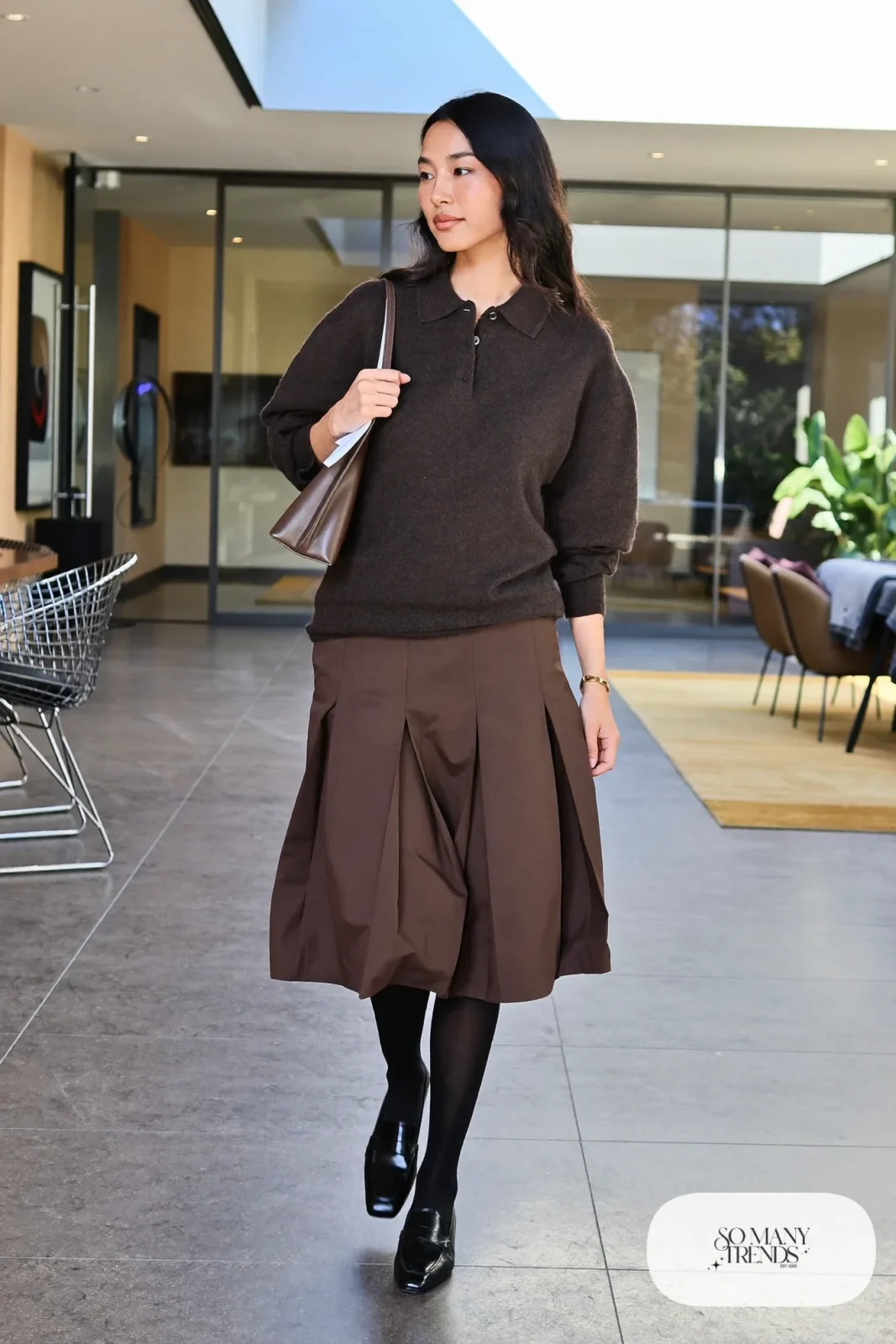 Woman in a charcoal knit polo, mocha pleated midi skirt, black tights and loafers, outfit 11