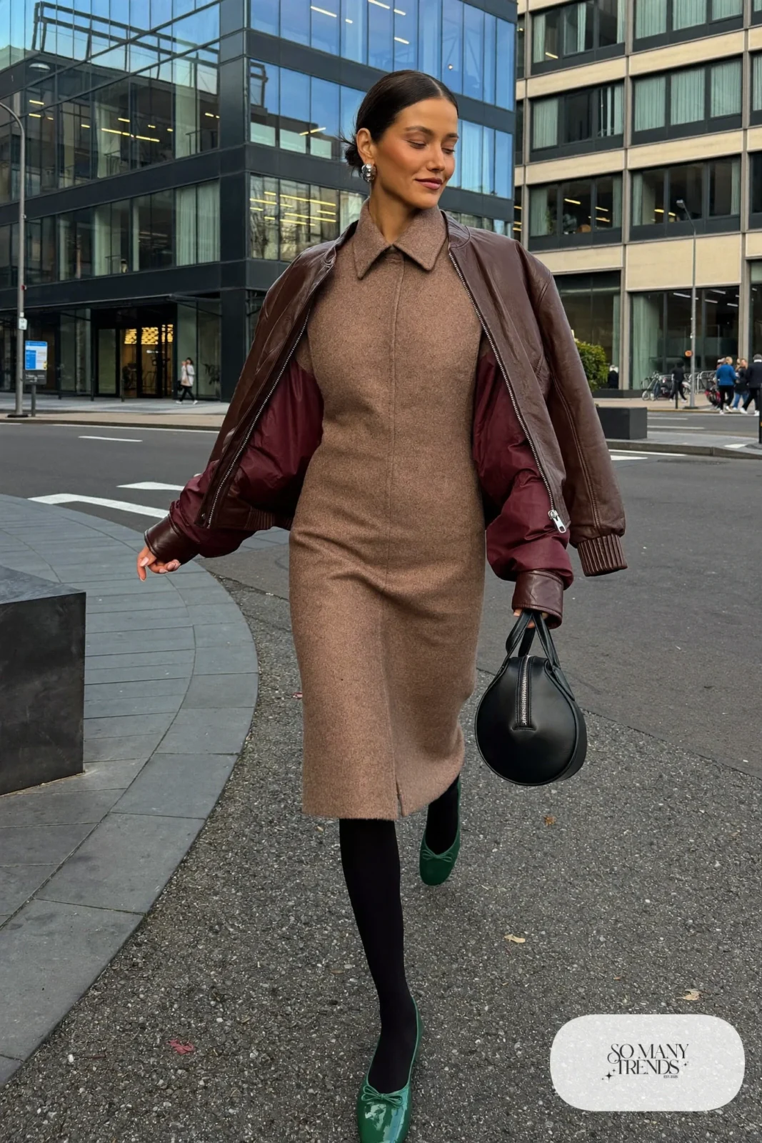 Woman in a taupe collarless coat dress with a brown leather bomber, dark flats and a black dome bag, outfit 22