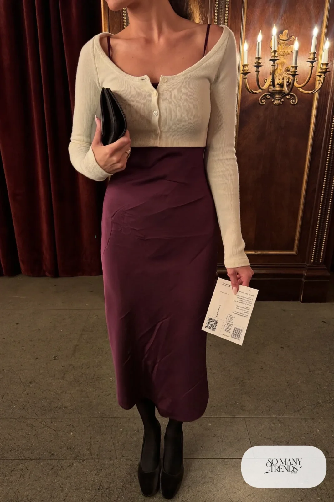 Woman in a plum satin midi slip dress, cream cropped cardigan, black opaque tights and black pumps, outfit 2