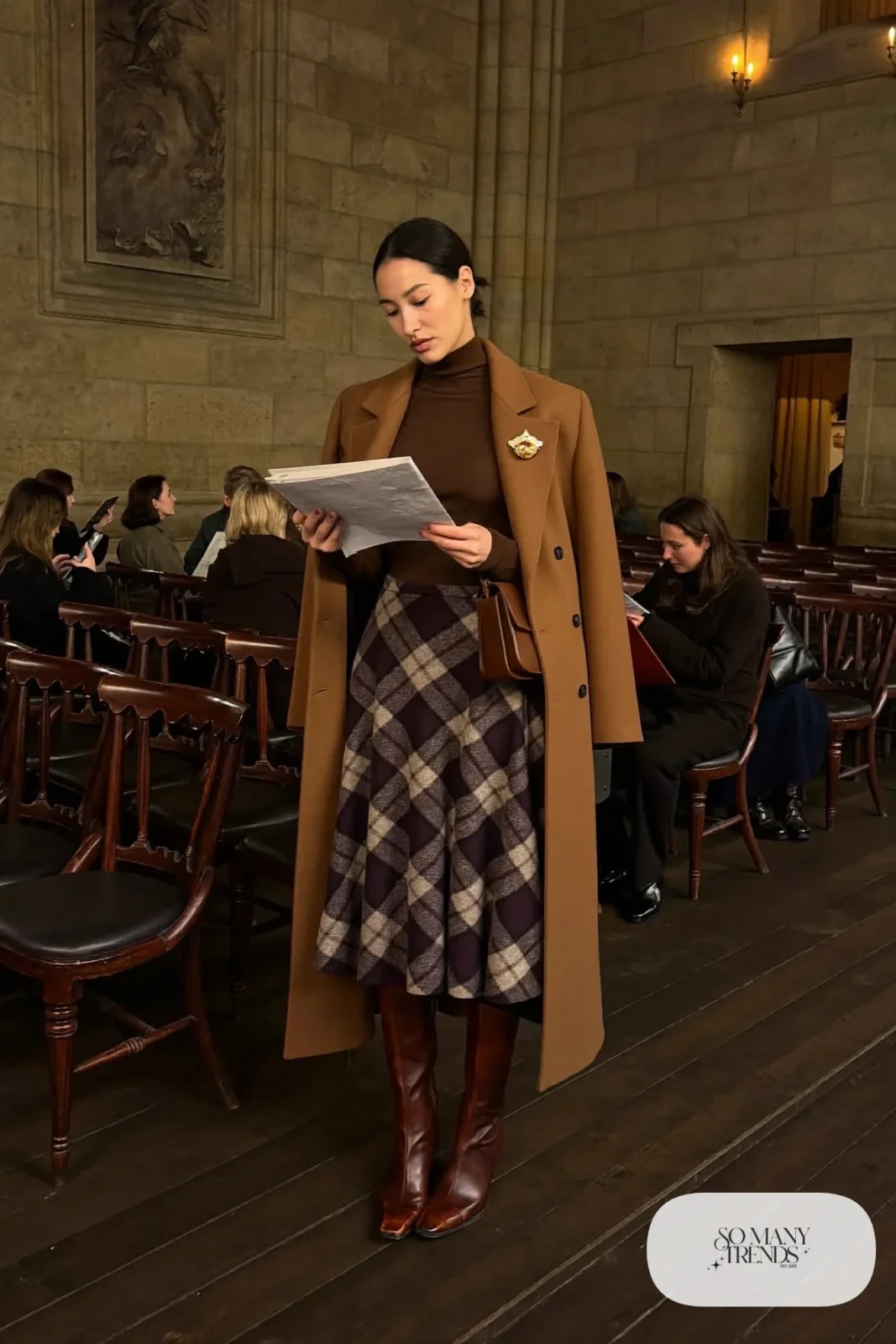 Woman in a plum and gray plaid wool midi skirt, chocolate turtleneck, brown tall boots and brooch, outfit 8