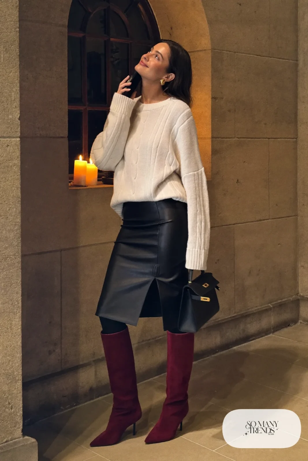Woman in a black leather midi skirt, cream cable knit sweater and burgundy suede boots, outfit 10