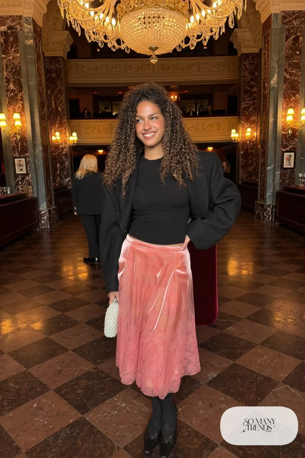 Woman in a dusty rose tulle midi skirt, fitted black long sleeve top, cropped black wool jacket and black ballet flats, outfit 11