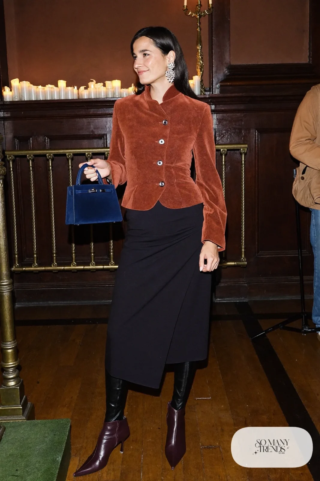 Woman in a rust peplum jacket, navy wrap midi skirt, oxblood pointed boots and chandelier earrings, outfit 23