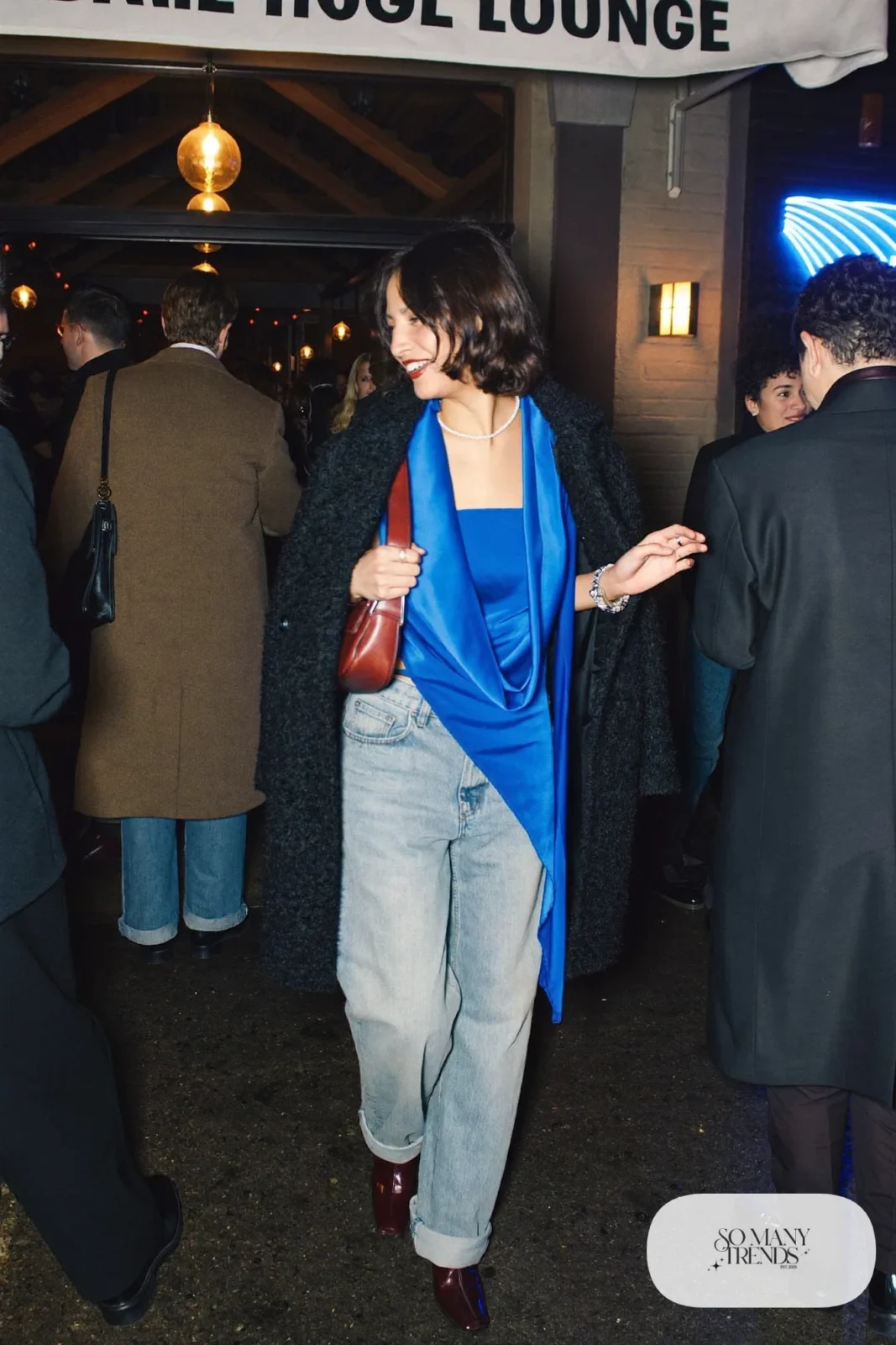 Cobalt satin cowl neck top with light barrel jeans, long black coat and oxblood pointed booties, outfit 4