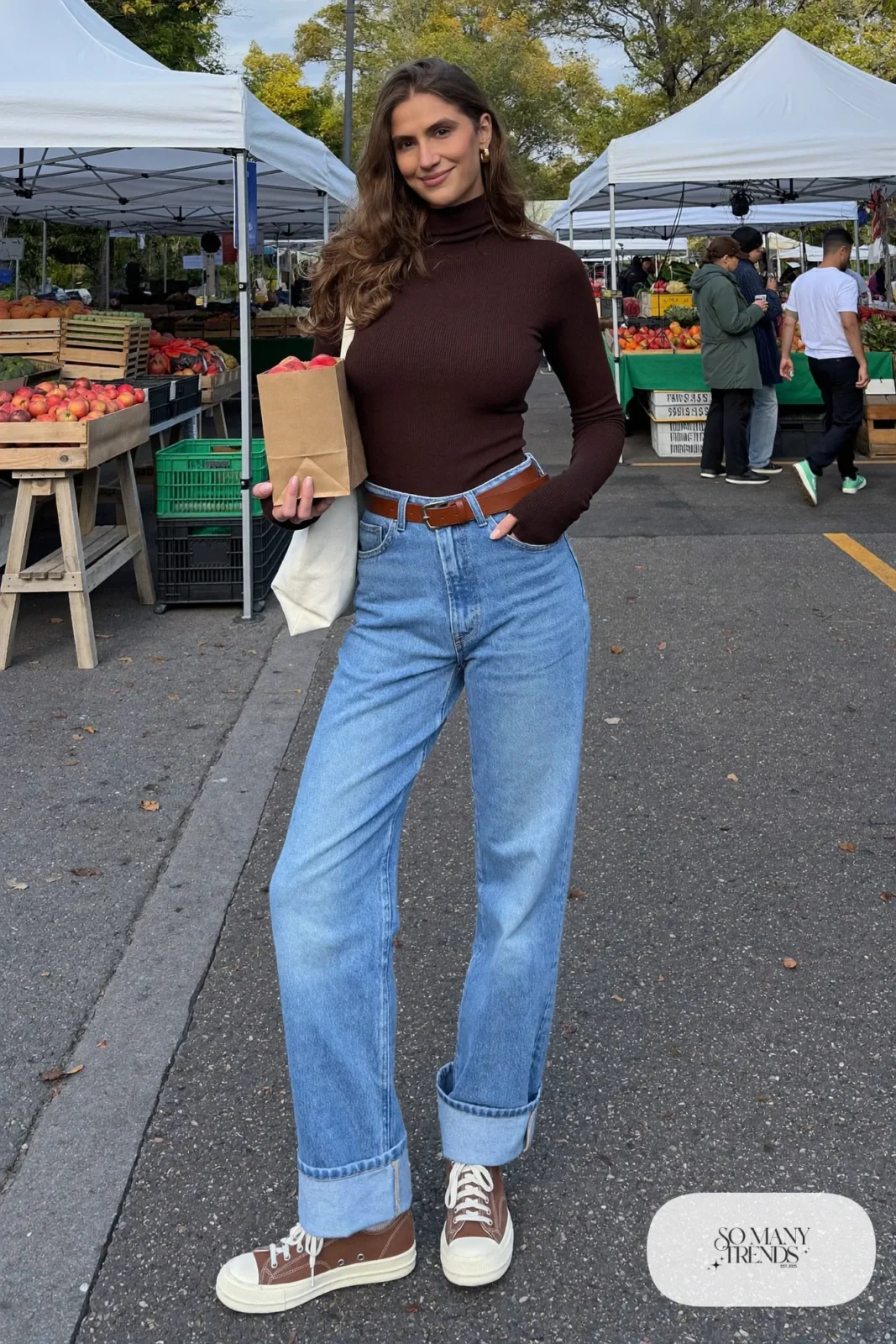 Chocolate brown fitted turtleneck tucked into sky blue barrel-leg jeans with a cognac belt and white-sole brown sneakers, outfit 3