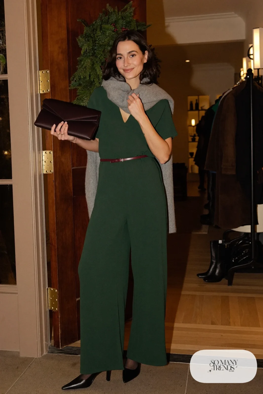 Woman in forest green wide-leg jumpsuit with burgundy leather belt, wine clutch and black closed-toe heels, outfit 3