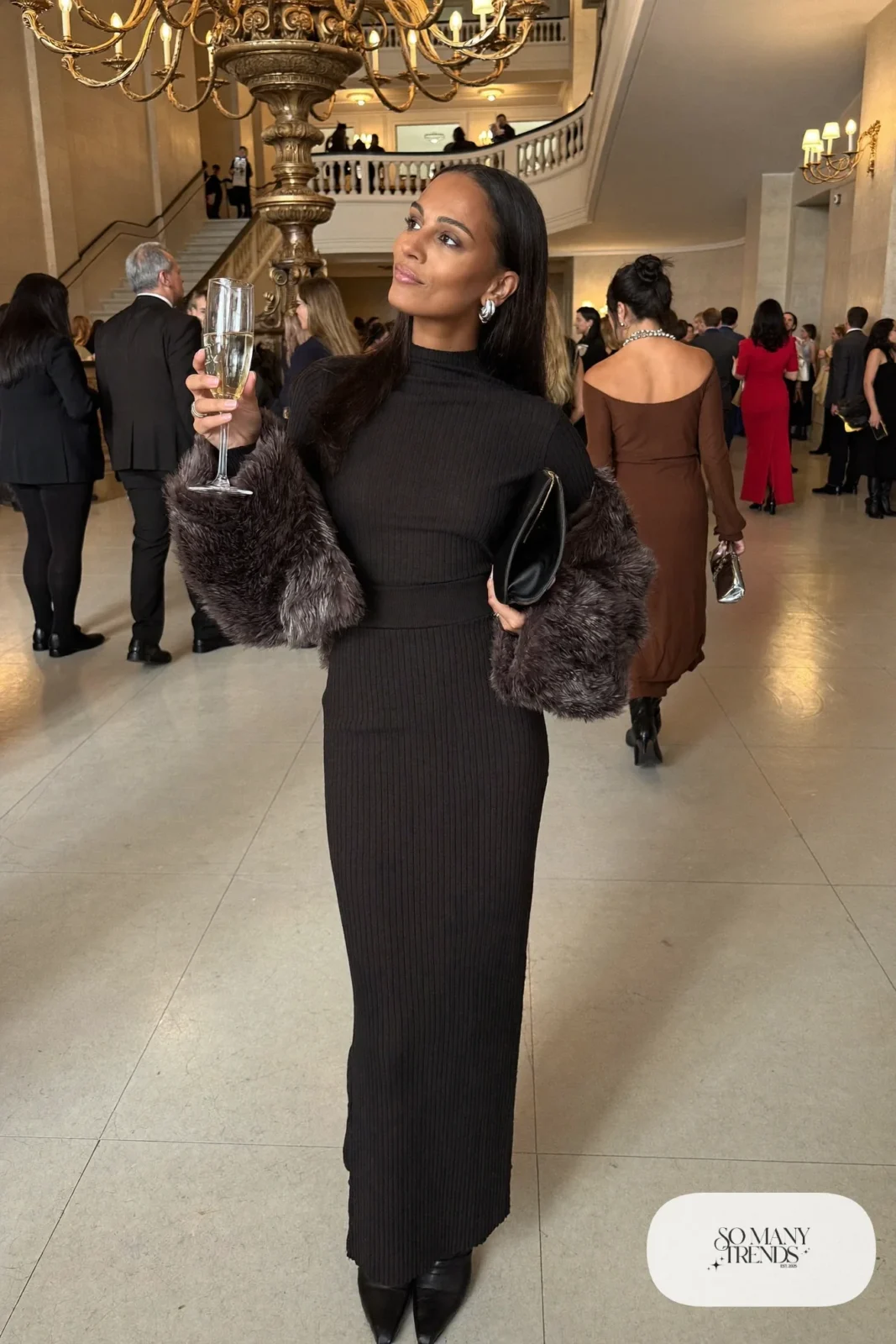 Woman in a black knit maxi dress, cropped gray faux fur jacket and black ankle-length pointed boots, theater outfit 6