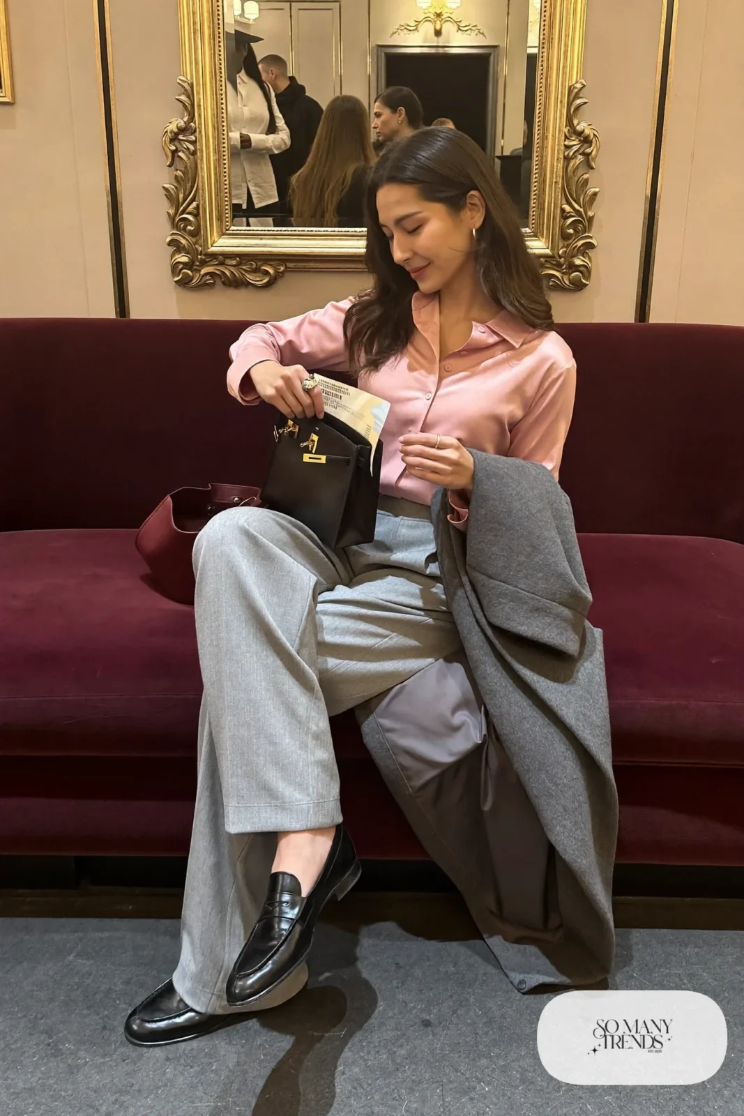 Woman in light gray wide-leg pants, dusty pink satin shirt, long gray coat, burgundy bag and black loafers, theater outfit 17