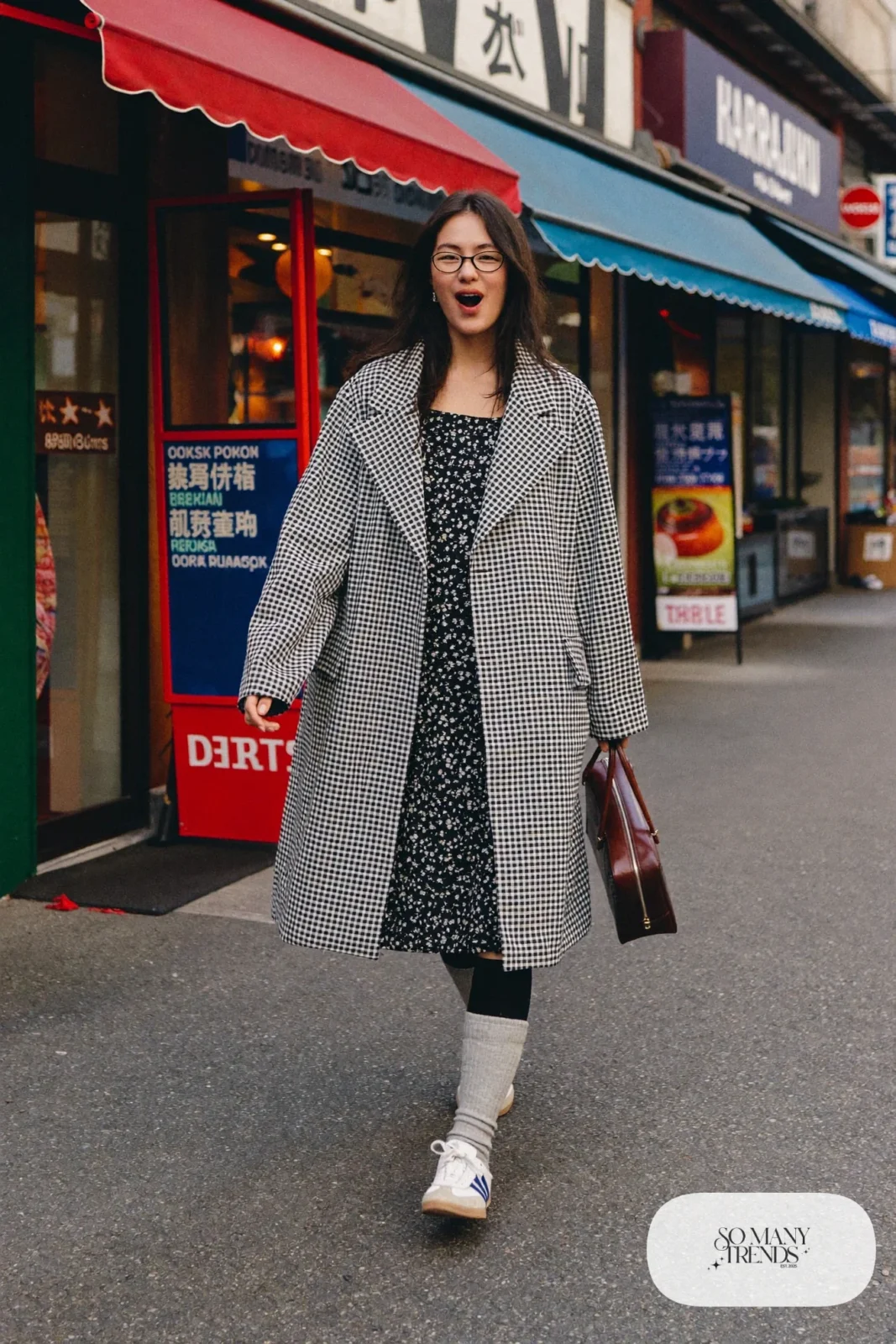 Woman in an oversized black and white gingham coat over a black and white floral midi dress with gray knee socks and retro sneakers, outfit 12