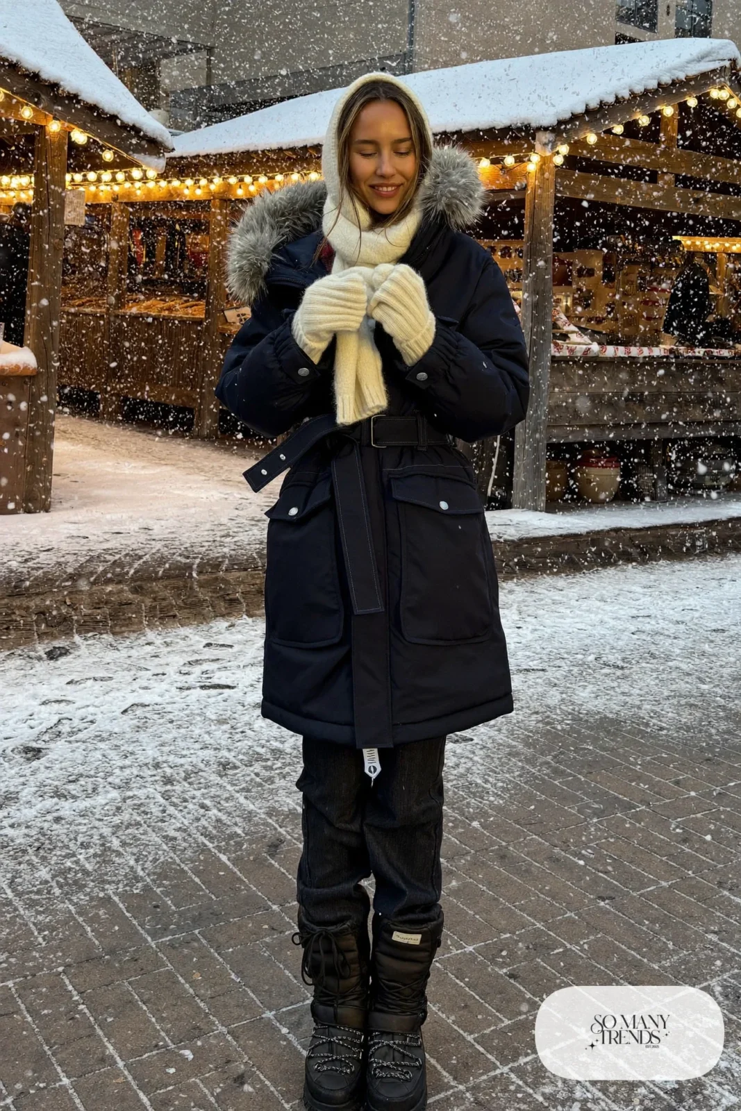 Woman in a navy long parka with a faux fur hood, thermal straight jeans and black insulated boots at a snowy Sapporo market, outfit 15