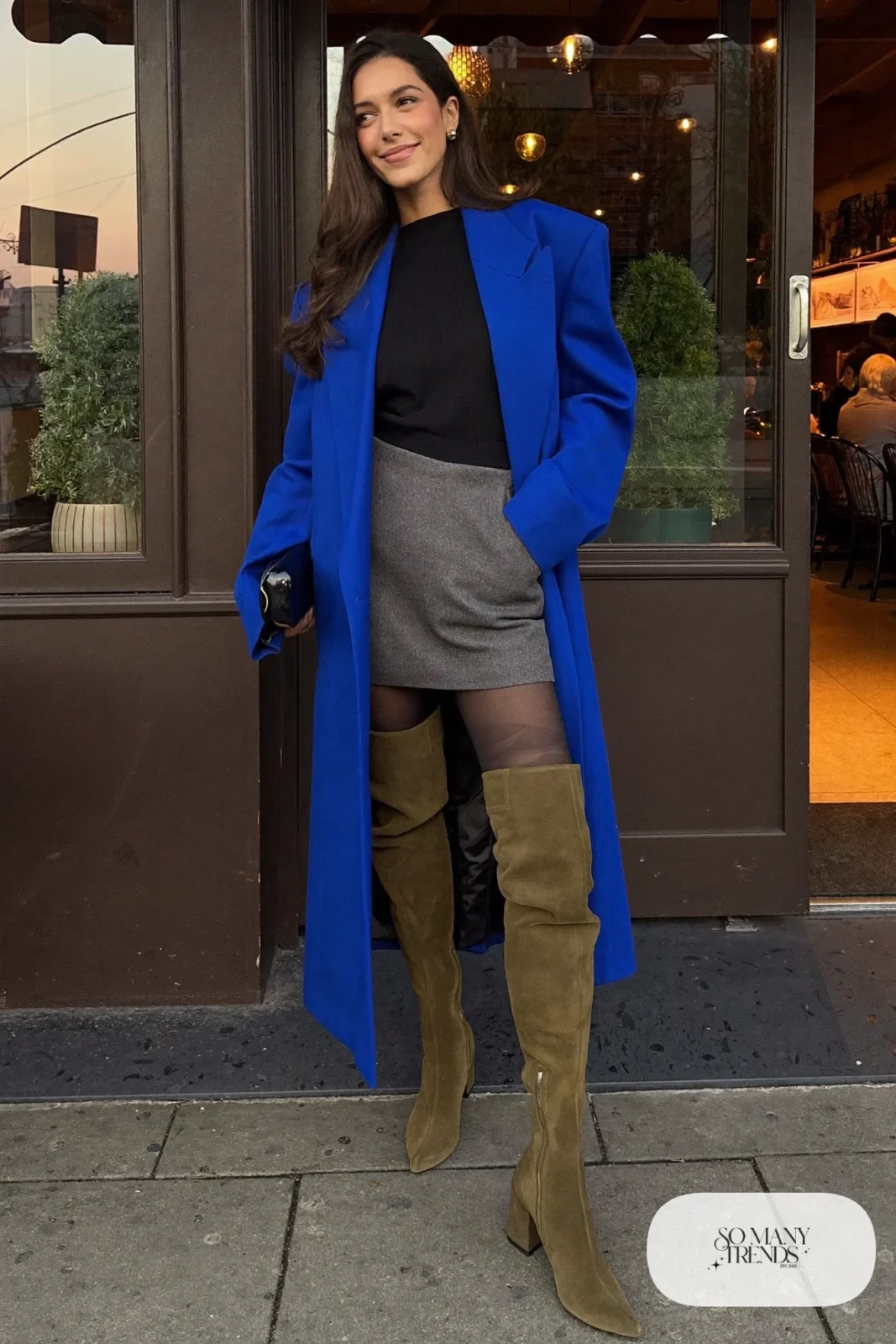 Woman in cobalt oversized blazer, black knit top, short gray wool skirt and olive suede over-the-knee boots, outfit 3