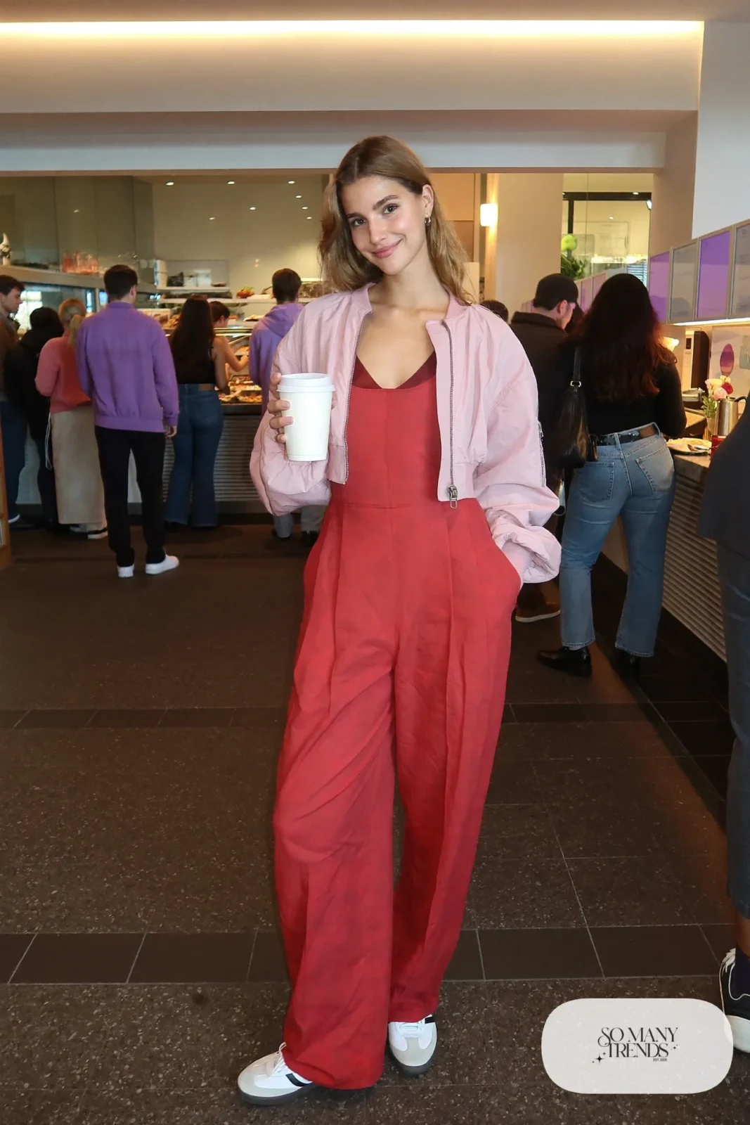 Woman in a tomato red wide-leg jumpsuit under a cropped pink bomber jacket with white sneakers, outfit 20