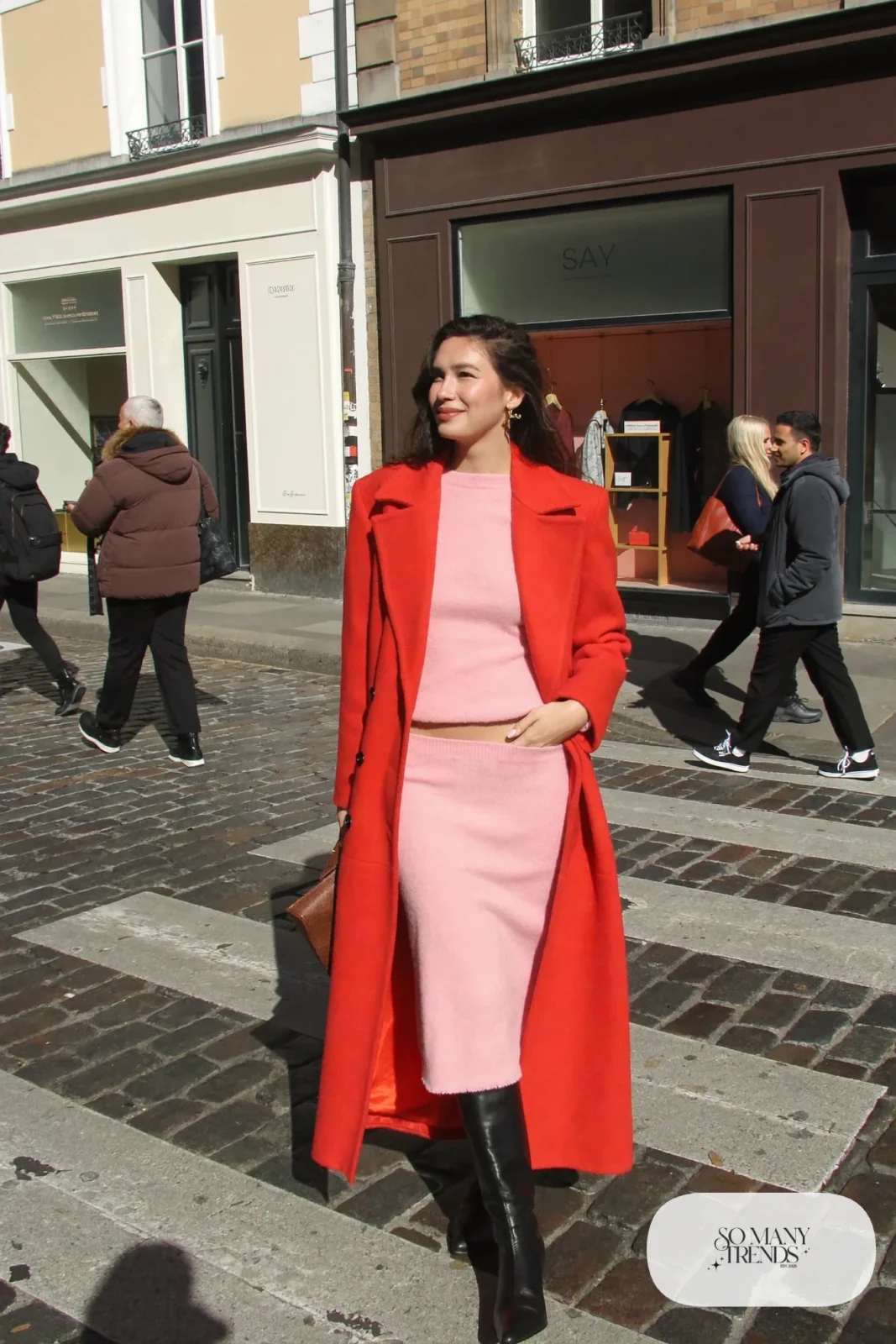 Woman in a long red wool coat over a pink knit top and midi skirt set with black boots, outfit 23