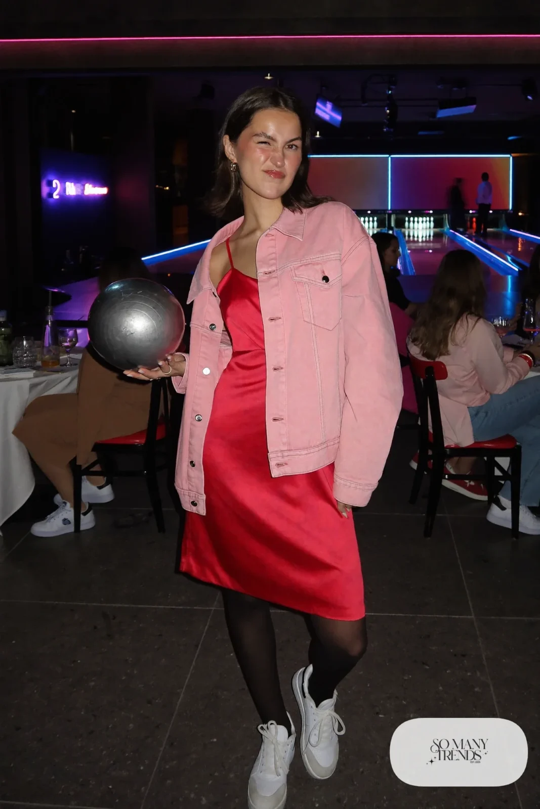 Woman in a pink denim jacket over a red slip dress with sheer tights and white sneakers, outfit 24