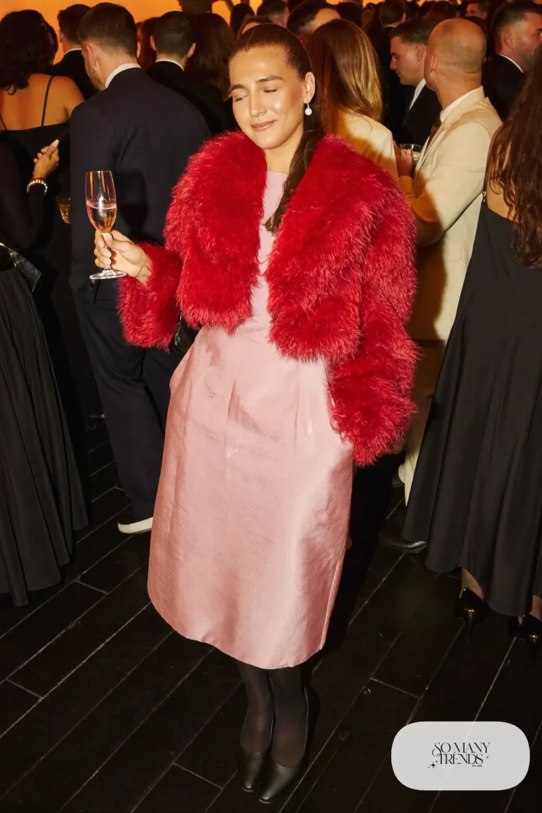 Woman in a cropped red faux fur jacket over a pink midi dress with sheer tights and black pumps, outfit 29