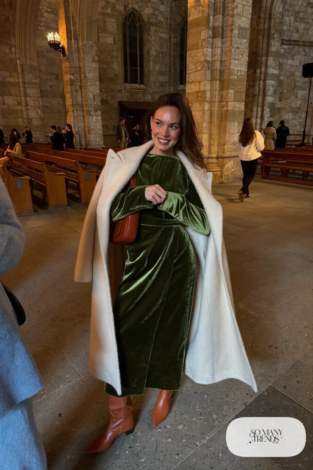 Woman in a moss green velvet wrap midi dress, oversized cream wool coat and cognac knee-high boots, outfit 1