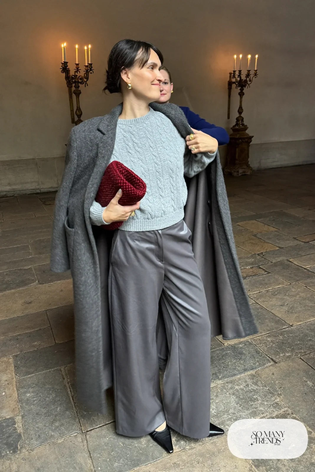 Woman in a heather gray cable knit sweater, long gray cardigan, mid gray wide pants and burgundy knit clutch, outfit 21