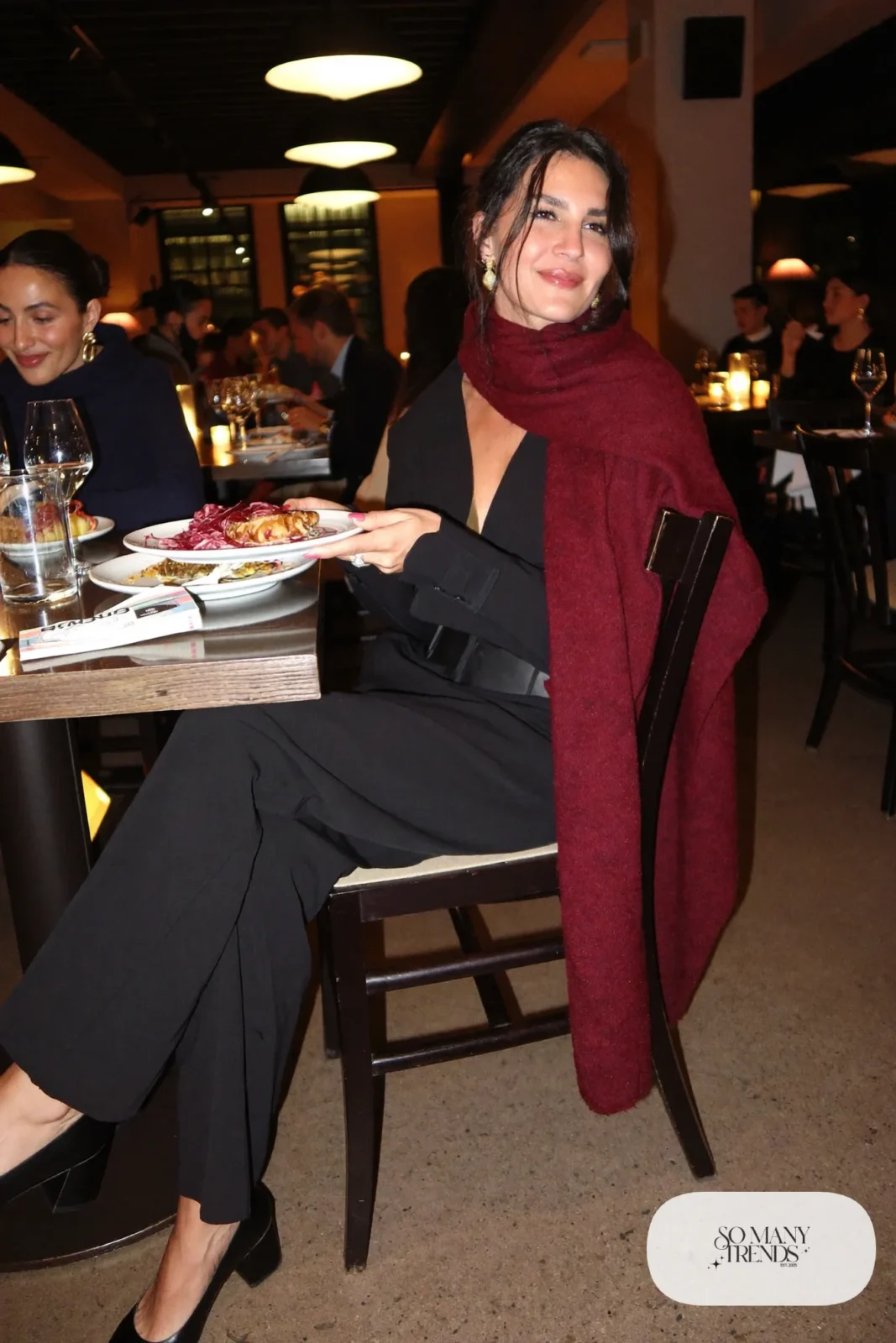 Woman in a black wide-leg jumpsuit, burgundy cashmere wrap and black block-heel pumps, theater outfit 20