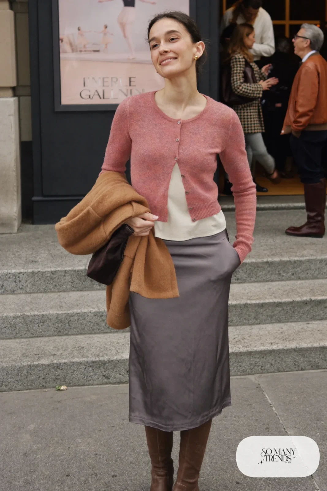 Woman in a cropped dusty pink cardigan, gray satin midi skirt, cream top and brown knee-high boots, theater outfit 28