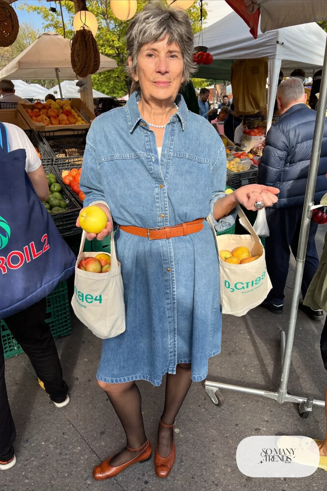 Petite woman in a belted denim shirt dress below the knee with brown belt and brown flats, outfit 3