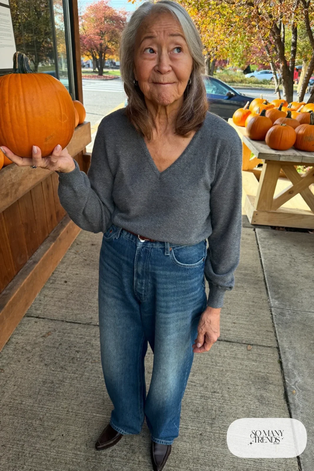 Petite woman in high-waisted straight denim jeans with a tonal blue V-neck sweater and brown loafers, outfit 9