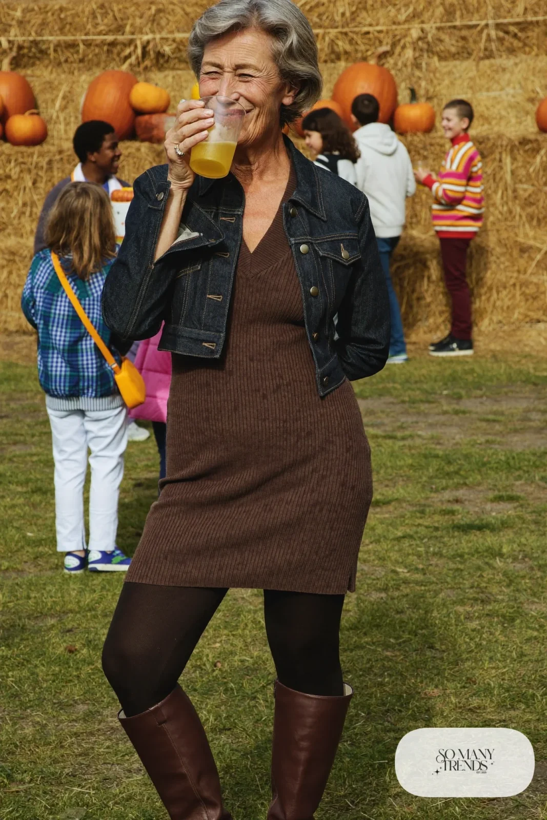Petite woman in a short denim jacket over a brown knit midi dress with tall brown boots, outfit 17