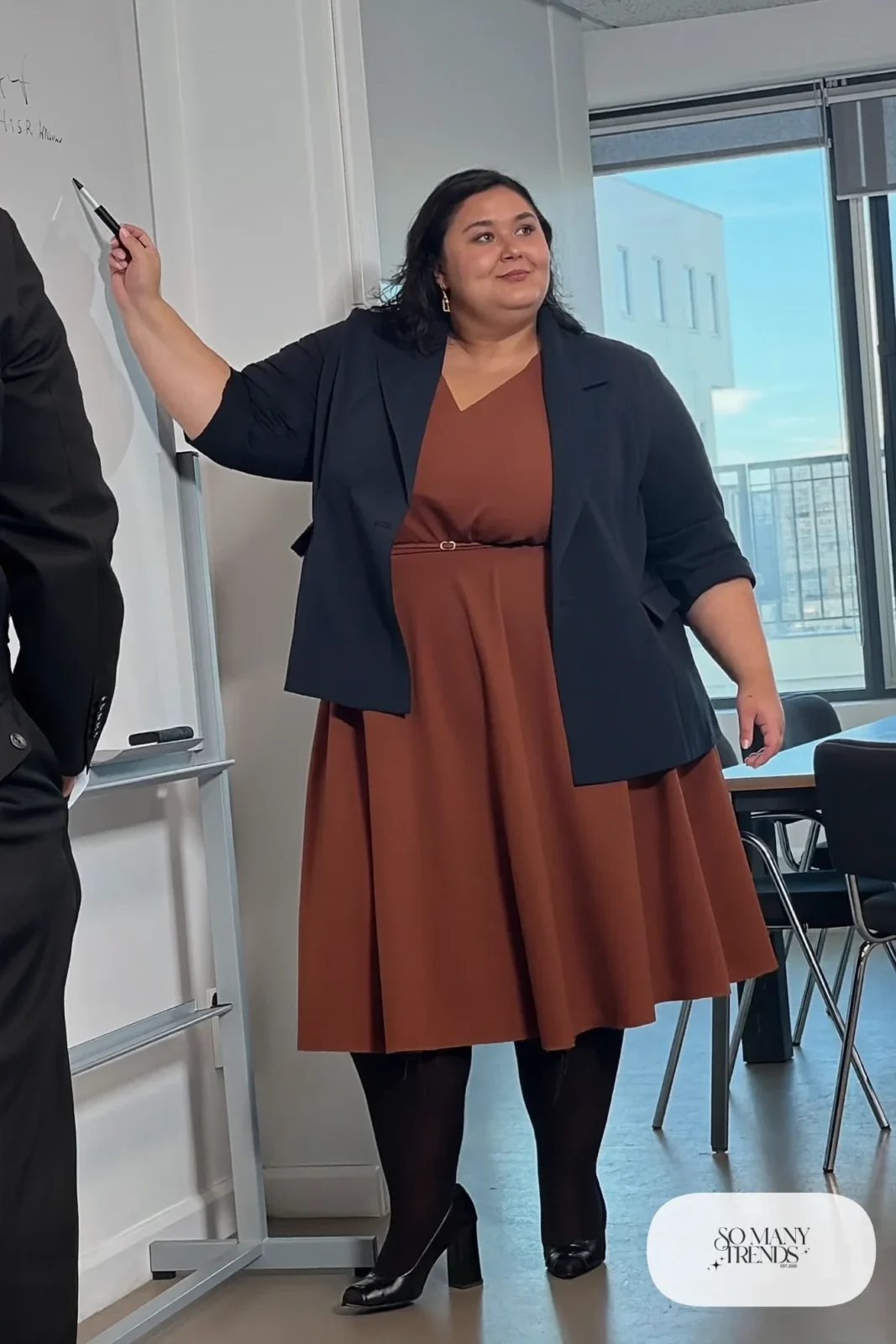 Woman in rust ponte V-neck midi dress, navy structured blazer, black tights and block-heel pumps, outfit 25