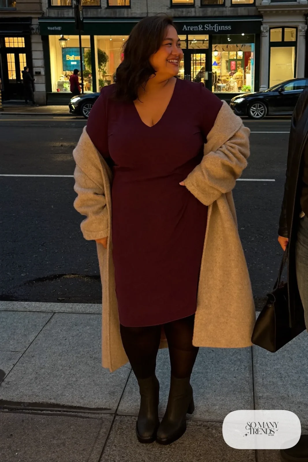 Woman in plum crepe V-neck midi dress, oatmeal wrap coat, black block-heel boots and structured bag, outfit 33
